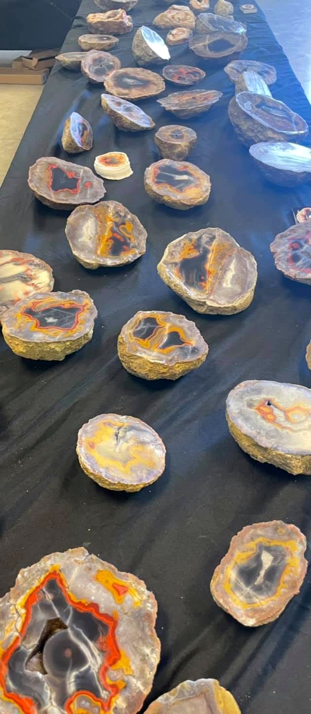 Agate slices laid out on dark cloth, highlighting the varied banding and colors revealed by cutting.